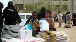 Dua bocah menerima bantuan yang diberikan oleh Komisaris Tinggi PBB untuk Pengungsi (UNHCR) di kota Hodeidah, Yaman (11/4). Perang di Yaman telah menewaskan lebih dari 10 ribu orang dan membuat lebih dari dua juta orang mengungsi. (AFP Photo/Abdo Hyder)