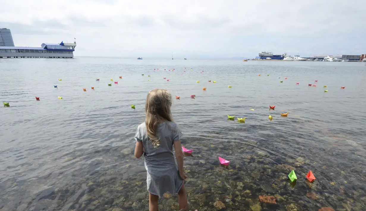 Seorang anak perempuan melihat-lihat perahu kertas yang diluncurkan saat perayaan 69 tahun akhir Perang Dunia II di Timur Jauh Vladivostok, Rusia, (2/9/2014). (REUTERS/Yuri Maltsev)