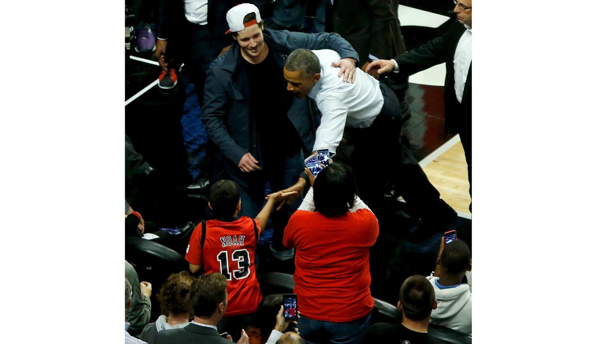 President Amerika Serikat Barack Obama menyalami penonton pada pembukaan NBA antara  Cleveland Cavaliers melawan Chicago Bulls di Chicago, Selasa(27/10/2015). (REUTERS / Jonathan Ernst)