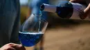 Seseorang menuangkan anggur biru 'Gik Life' ke gelas di pabrik pembuat anggur di Maluenda, wilayah Aragon, Spanyol, 13 September 2018. Warna biru ini diyakini memberi kesan pada perubahan dan inovasi yang tak terhingga. (AFP/GABRIEL BOUYS)