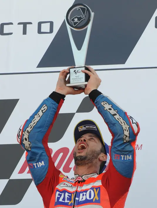 Pembalap Ducati Andrea Dovizioso, melakukan selebrasi di atas podium setelah memenangkan GP Inggris di Sirkuit Silverstone, Minggu (27/8). Dengan kemenangan ini, Dovizioso menggeser Marquez dari puncak klasemen sementara MotoGP. (AP Photo/Rui Vieira)