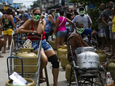 Warga memakai masker saat antre membeli gas murah dari Petrobrás Oil Tankers Union di favela Vila Vintem, Rio de Janeiro, Brasil, Jumat (12/3/2021). Kegiatan ini sebagai kampanye solidaritas untuk memperingati Hari Perjuangan Nasional Pertahanan Perusahaan Milik Negara. (AP Photo/Bruna Prado)