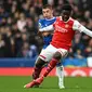 Gelandang Arsenal, Bukayo Saka, mendapatkan pengawalan dari bek Everton, Vitaliy Mykolenko, pada pertandingan pekan ke-22 Premier League 2022/2023 yang digelar di Goodison Park, Sabtu (4/2/2023) malam WIB. (AFP/Paul Ellis)