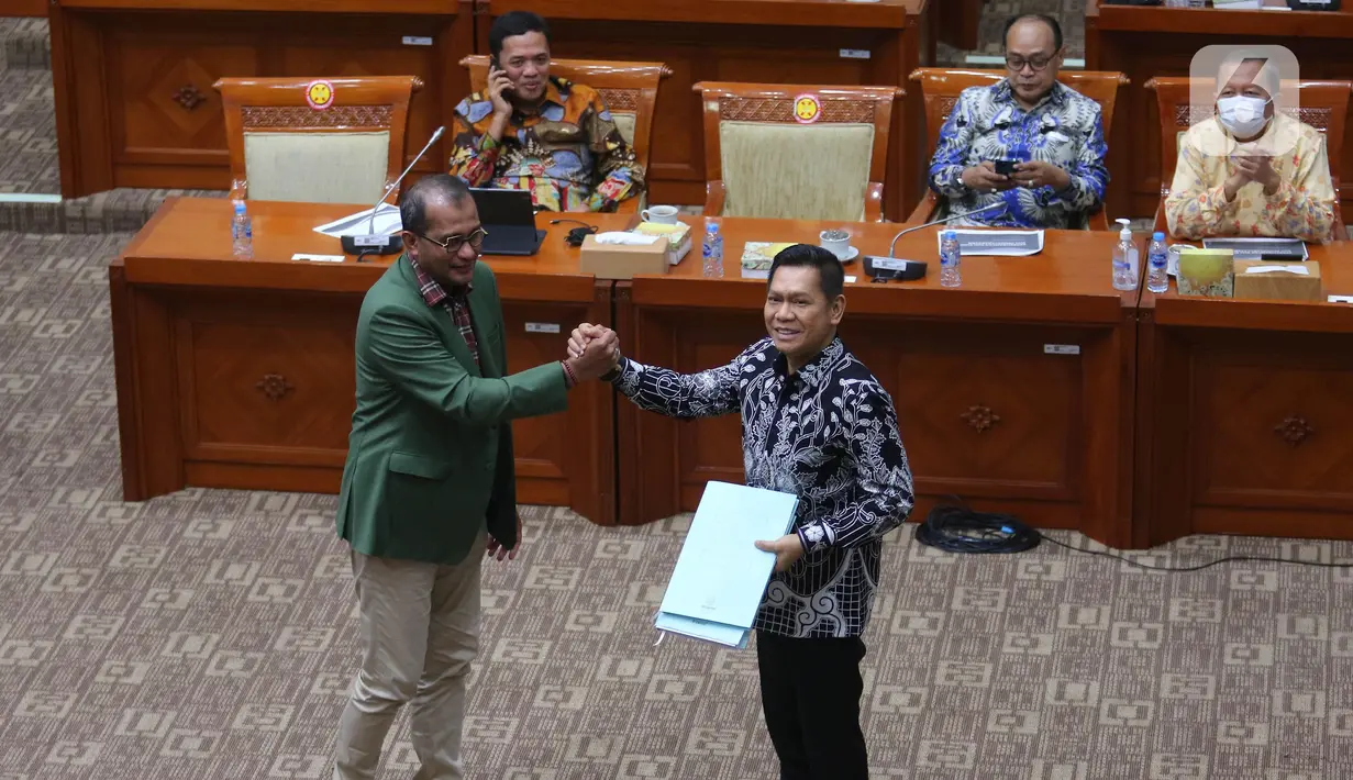 Wakil Menteri Hukum dan HAM Edward Omar Sharif Hiariej (kiri) saat menyerahkan naskah RUU KUHP dan RUU tentang Permasyarakatan yang telah disempurnakan  kepada Wakil Ketua Komisi III DPR Adies Kadir (kanan)  saat rapat kerja bersama Komisi III DPR di Kompleks Parlemen, Senayan, Jakarta, Rabu (6/7/2022). (Liputan6.com/Angga Yuniar)