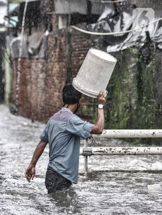 Seorang pria menerobos banjir yang merendam Jalan Abdullah Syafei, Tebet, Jakarta, Kamis (18/2/2021). Banjir juga menyebabkan akses putar balik di kawasan dekat Stasiun Tebet itu terputus. (merdeka.com/Iqbal S Nugroho)