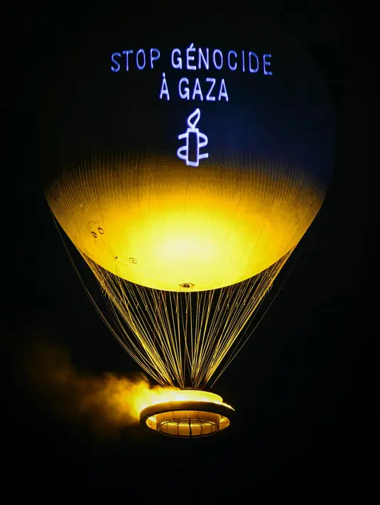 Aksi tersebut untuk mendesak diberlakukannya gencatan senjata dan dihentikannya genosida yang sedang berlangsung di Gaza, Palestina, oleh pasukan pendudukan Israel. Tampak dalam foto, sebuah pesan bertuliskan “Hentikan genosida di Gaza” diproyeksikan ke kaudron Olimpiade Paris 2024, yang dirancang oleh perancang Prancis Mathieu Lehanneur, di Paris, pada 26 Juli 2025. (Hugo MATHY/AFP)