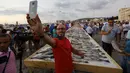 Seorang pria berfoto dengan latar belakang sejumlah ikan yang berhasil memecahkan rekor makanan laut terbanyak di daerah kota pantai Batroun, Minggu (4/9). Menurut panitia, total ikan yang dikumpulnya sebanyak 2 ton 614 kg. (AFP PHOTO/Anwar AMRO)