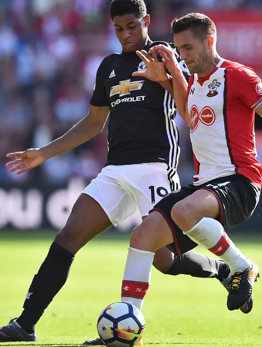 Striker Manchester United, Marcus Rashford, berebut bola dengan gelandang Southampton, Dusan Tadic, pada laga Premier League di Stadion St Mary's, Sabtu (23/9/2017). Manchester United menang 1-0 atas Southampton. (AFP/Glyn Kirk)