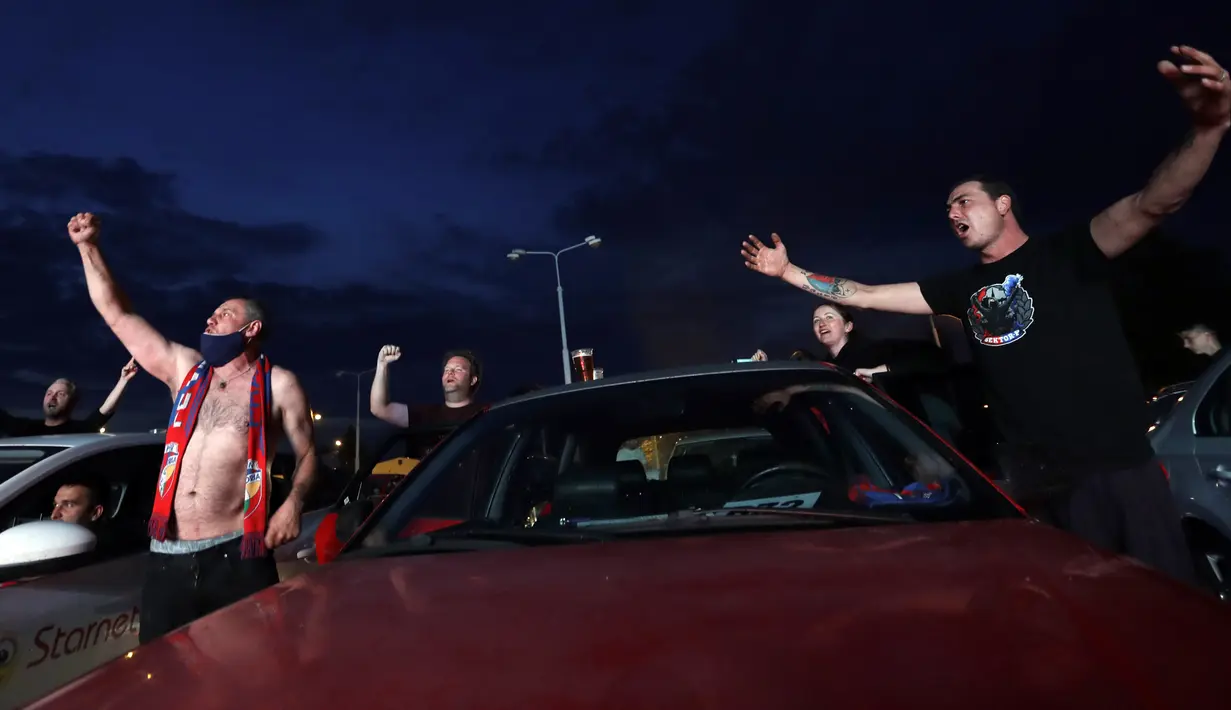 Para suporter bersorak saat menyaksikan pertandingan Viktoria Plzen dan Sparta Praha di sebuah bioskop drive-in di Pilsen, Republik Ceko, Rabu (27/5/2020). Di tengah pandemi COVID-19, suporter Ceko dapat menyaksikan pertandingan bola lewat layar di bioskop drive-in. (AP Photo/Petr David Josek)