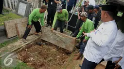 Pekerja membongkar makam fiktif di Tempat Pemakaman Umum (TPU) Menteng Pulo, Jakarta Selatan, Kamis (28/7). 4 makam di bongkar dari total terindikasi 14 makam fiktif yang ditemukan di TPU tersebut. (Liputan6.com/Gempur M Surya)