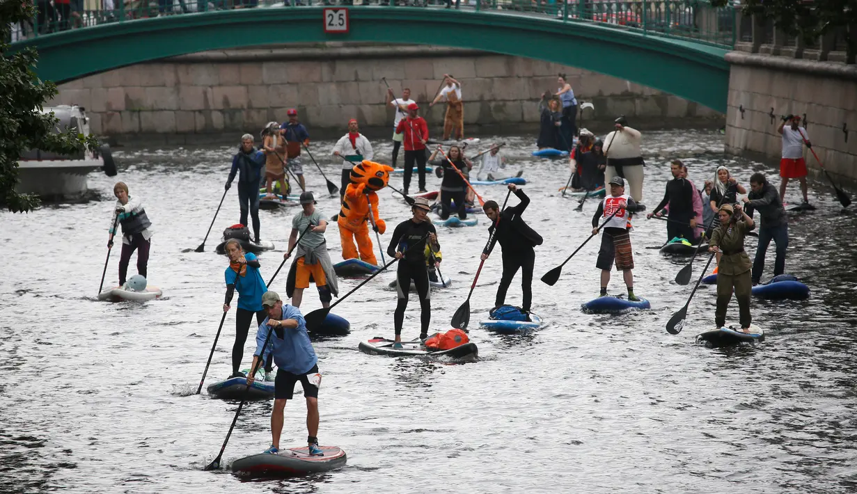 Orang-orang mendayung "paddle board" di sepanjang kanal Griboedov pada festival SUP (Stand Up Paddle)-Surfing di St.Petersburg, Rusia, Minggu (12/8). Dalam paddling, mereka menggerakkan papannya dengan cara mendayung sambil berdiri. (AP/Dmitri Lovetsky)