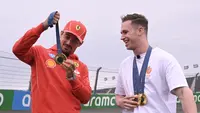 Pembalap Ferrari, Charles Leclerc berbincang sambil memegang medali emas Olimpiade Paris 2024 milik atlet balap sepeda track Belanda, Harrie Lavreysen menjelang Formula 1 GP Belanda di Sirkuit Zandvoort, Kamis (22/08/2024) waktu setempat. (AFP/John Thys)