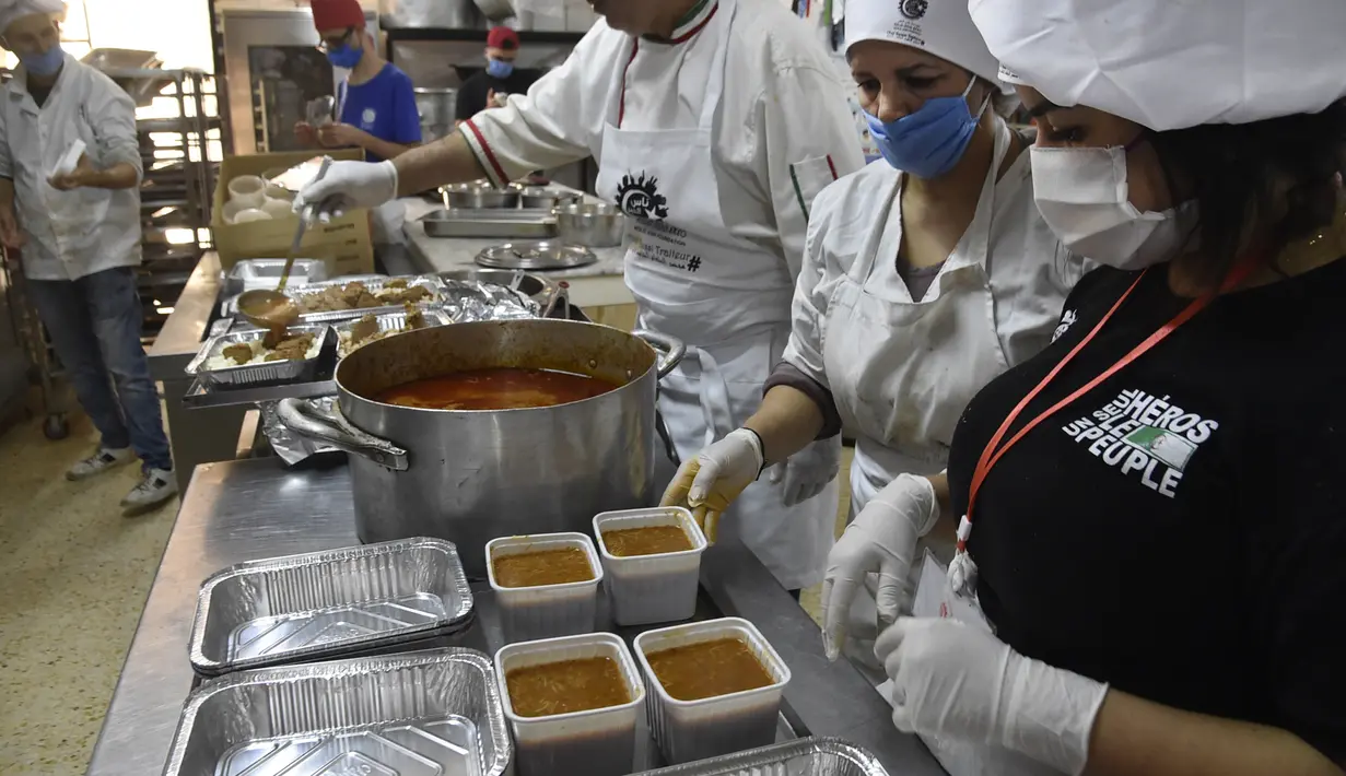 Relawan dari asosiasi Nass el-Khir mengemas kotak makanan sebelum didistribusikan kepada mereka yang membutuhkan selama bulan suci Ramadan di Aljir, Aljazair, Senin (18/5/2020). (RYAD KRAMDI/AFP)