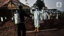 Petugas mengenakan alat pelindung diri (APD) dan baju hazmat saat proses pemakaman pasien Covid-19 di TPU Pondok Ranggon, Jakarta, Kamis (24/9/2020). Jumlah kumulatif kasus Covid-19 di Indonesia mencapai 262.022 orang per Kamis (24/9) dengan 10.105 jiwa meninggal dunia. (merdeka.com/Iqbal Nugroho)
