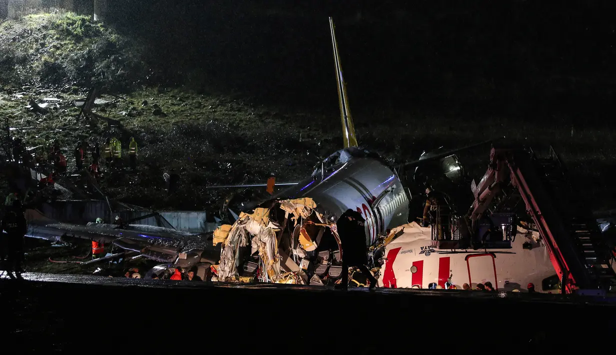 Tim penyelamat dan petugas pemadam kebakaran bekerja setelah sebuah pesawat tergelincir di landasan pacu Bandara Sabiha Gokcen, Istanbul, Turki, Rabu (5/2/2020). Kementerian Transportasi Turki menyebut kecelakaan akibat pendaratan yang keras. (Can Erok/DHA via AP)