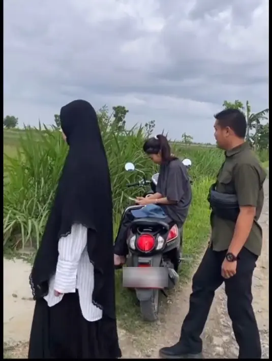 Saat sang suami turun dari motor dan melihat-lihat sawah, Azizah Salsha tampak duduk di motor. 
 [Youtube/momenbucin]