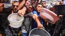 Warga Palestina berdesakan berebut makanan yang sudah dimasak dari dapur umum di Jabalia, Jalur Gaza Utara, pada 17 Mei 2025. (Bashar TALEB/AFP)
