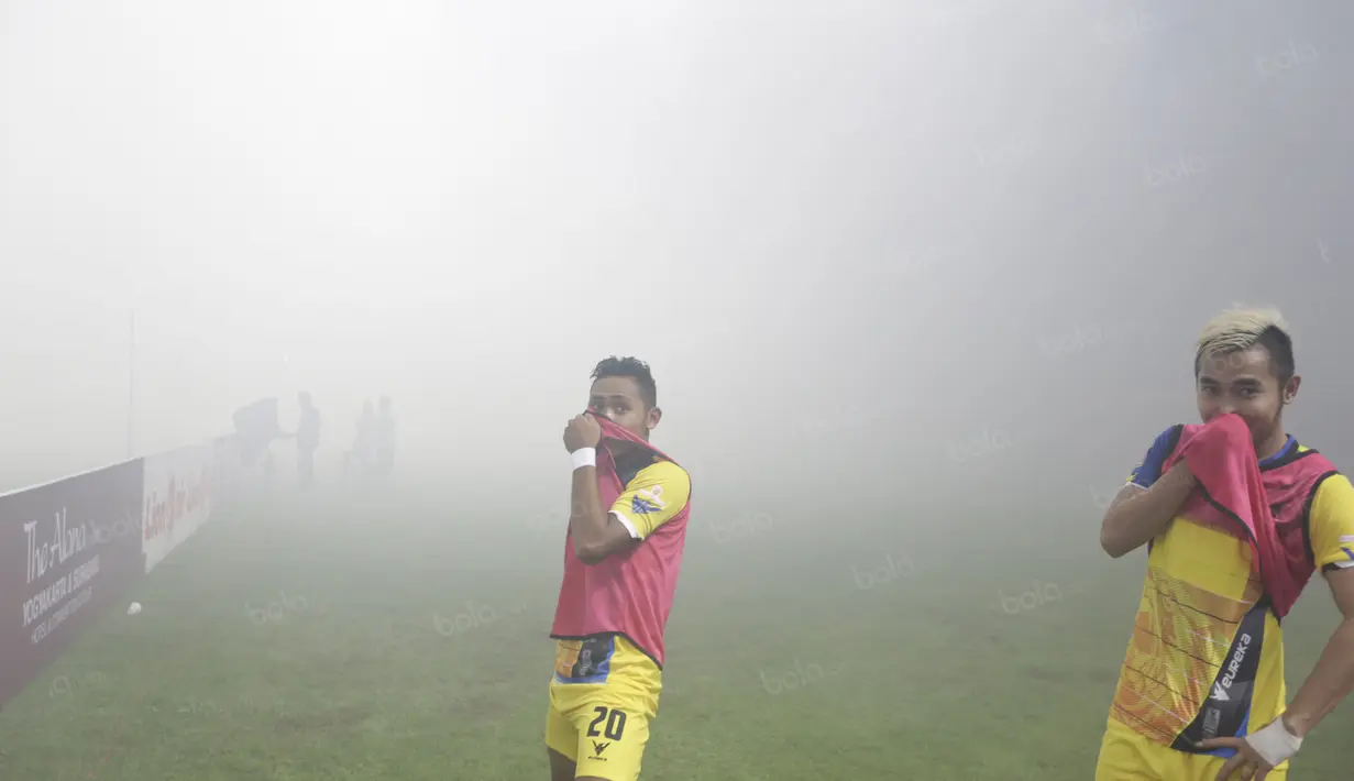 Pemain Persiba Balikpapan  menutup hidung  saat melakukan pemanasan akibat asap flare pada lagaTorabika SC 2016 di Stadion Gelora Bangkalan, Senin(13/6/2016).  (Bola.com/Nicklas Hanoatubun)