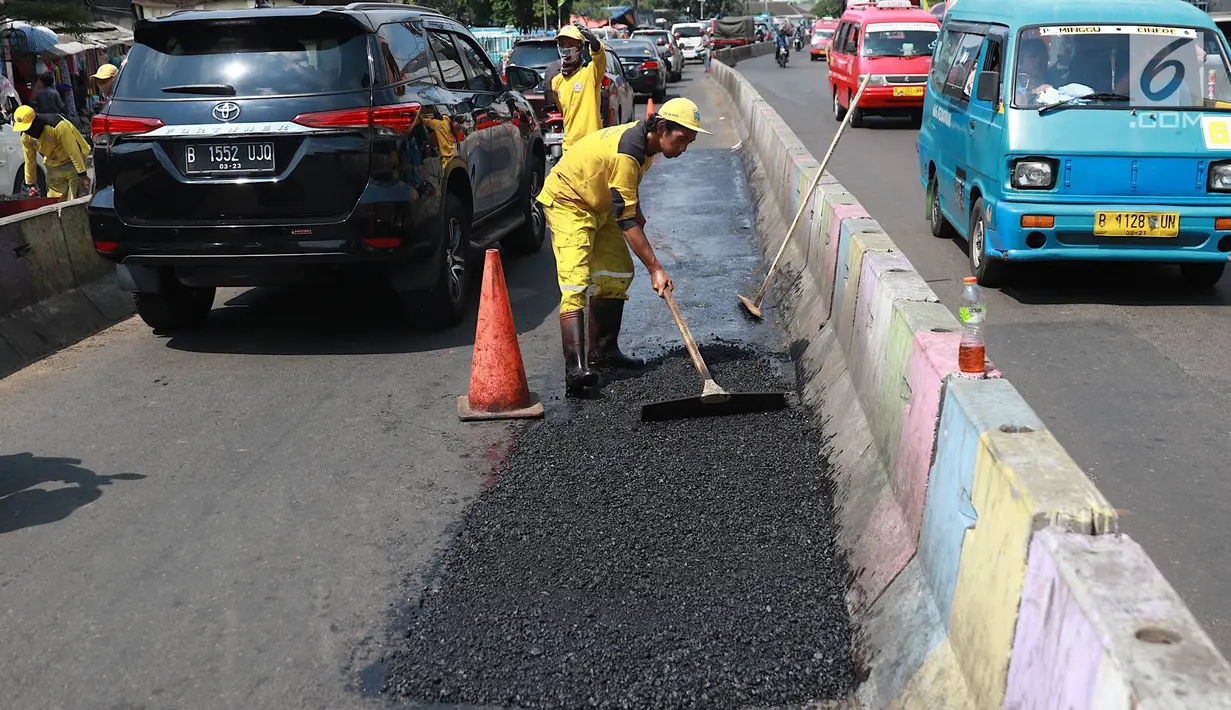 Petugas Bina Marga Pasar Minggu menambal jalan yang rusak di Jalan Raya Ragunan, Jakarta, Senin (22/4). Petugas mengaku bahwa keberadaan beton pembatas jalan justru membuat jalan di kawasan tersebut selalu rusak setiap hujan deras karena menimbulkan genangan air. (Liputan6.com/Immanuel Antonius)