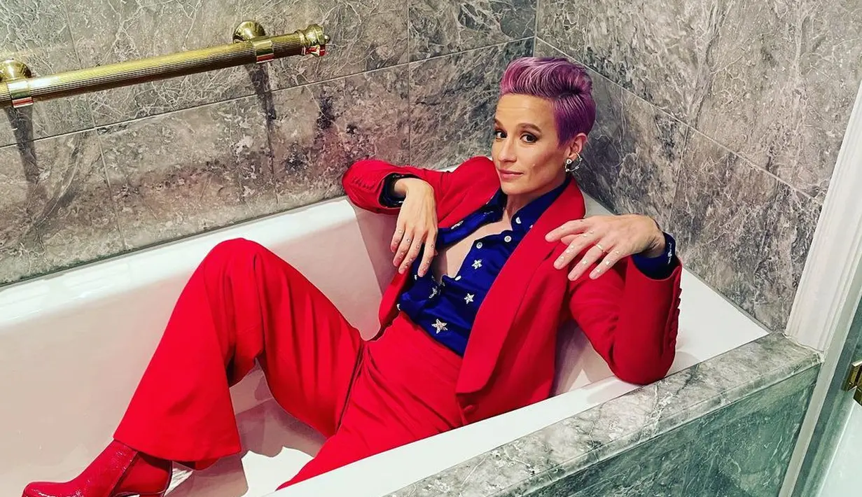 Kostum Megan Rapinoe juga sarat akan simbol Amerika Serikat. Setelan blazer dan celana panjang berwarna merah dilengkapi dengan kemeja biru dengan motif bintang, khas bendera Amerika Serikat. Foto: Instagram @mrapinoe.