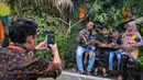 Untuk menyambut libur panjang Nataru 2025/2026, pengelola Kebun Binatang Surabaya (KBS) telah menyiapkan sejumlah program dan hiburan khusus bagi para pengunjung. Tampak dalam foto, seorang karyawan kebun binatang (kiri) mengambil foto sebuah keluarga yang memegang ular piton di Kebun Binatang Surabaya, Jawa Timur, selama libur sekolah sekaligus jelang Natal dan Tahun Baru pada Minggu 21 Desember 2025. (JUNI KRISWANTO/AFP)