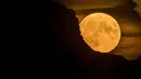 Bulan super purnama, muncul di balik gunung di Pegunungan Alpen Swiss, terlihat dari Chexbres, Swiss barat, Rabu (13/7/2022). Bulan Purnama dikenal sebagai Buck Moon dan juga Supermoon. Di kondisi ini Bulan akan terlihat tampak lebih besar dan terang sehingga terasa sangat dekat dari Bumi. (Fabrice COFFRINI / AFP)