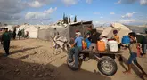 Warga dan anak-anak Palestina mengangkut jeriken berisi air bersih dari tangki air bergerak dengan gerobak keledai di kamp pengungsi Bureij di Jalur Gaza tengah pada 6 Oktober 2025. (Eyad BABA/AFP)