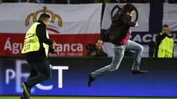 Petugas berusaha mengamankan supporter yang menerobos masuk lapangan pada laga perempat final leg pertama Liga Champions antara Wolfsburg melawan Real Madrid di Stadion Volkswagen Arena, Jerman, Rabu (6/4/2016). (AFP/John Macdougall)