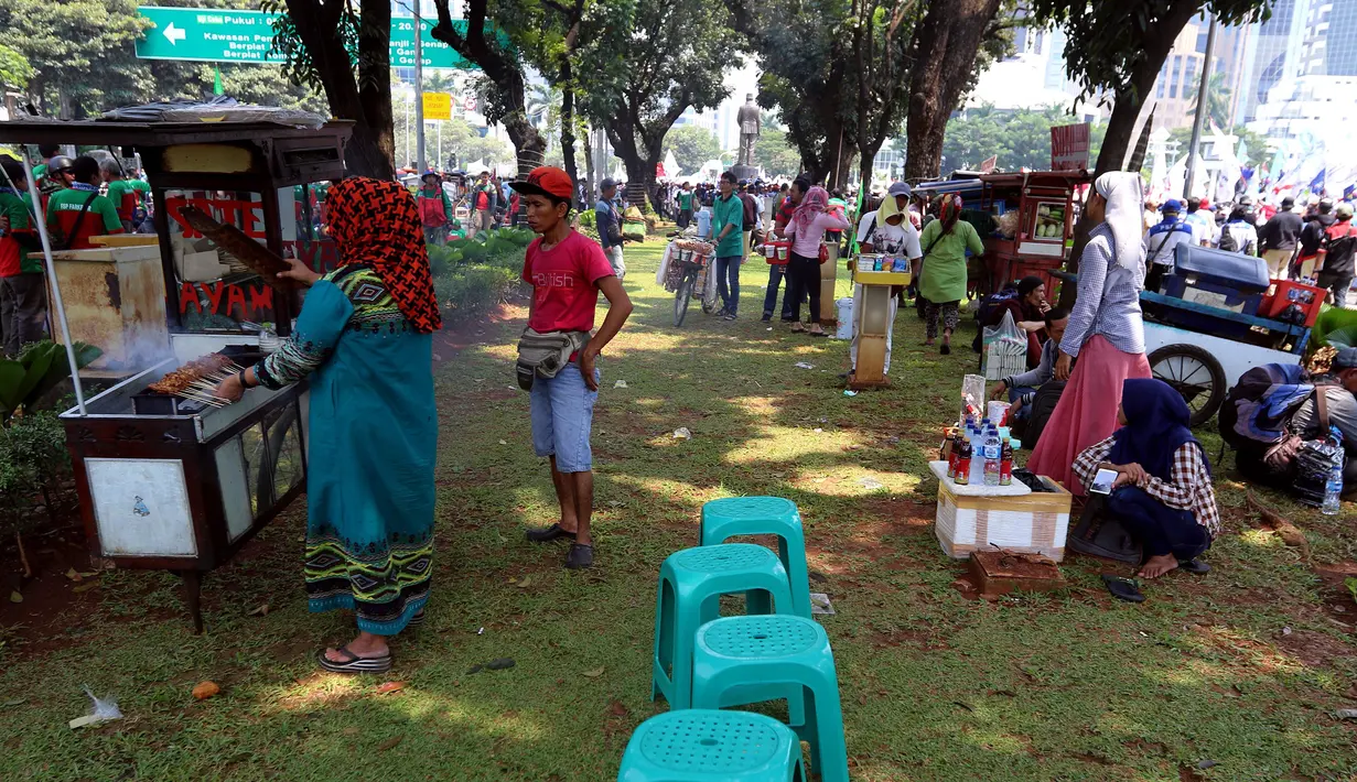 Pedagang kaki lima menjajakan barang dagangan saat Demo Hari Buruh di Jakarta, Selasa (1/5). Pedagang kaki lima ini memanfaatkan Hari Buruh untuk mengais rejeki dengan berjualan saat demontrasi berlangsung. (Liputan6.com/Johan Tallo)
