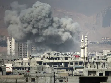 Kepulan asap membubung tinggi usai terjadi serangan udara dari pasukan Assad di wilayah Ghouta Timur, Suriah (7/2). Akibat serangan ini dilaporkan sedikitnya, 47 warga sipil tewas. (AFP Photo/Amer Almohibany)