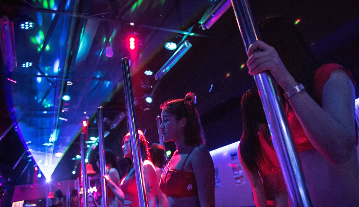Sejumlah wanita penghibur berdiri sambil menunggu pengunjung di sebuah bar di kawasan Walking Street, Pattaya, Thailand (29/3). (AFP/ Roberto Schmidt)