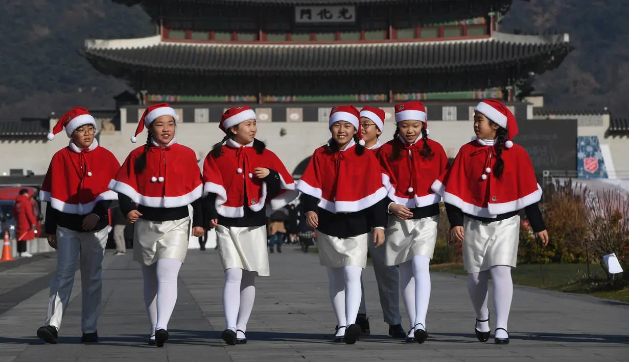 Anak-anak Korea Selatan mengenakan pakaian Santa Claus berjalan di depan Istana Gyeongbokgung, Seoul, Jumat (30/11). Anak-anak tersebut bersiap meluncurkan kampanye penggalangan dana akhir tahun dari The Salvation Army. (Jung Yeon-je/AFP)