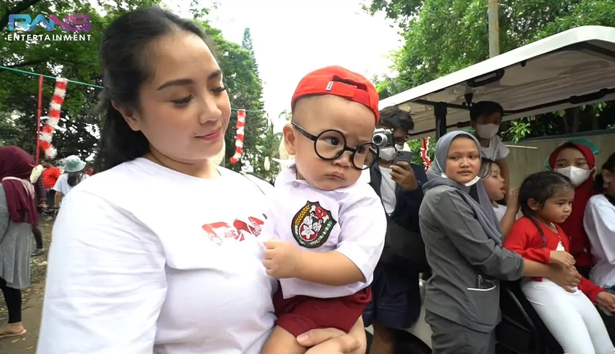 Digendong oleh Nagita Slavina, Rayyanza Malik Ahmad memakai seragam SD lengkap dengan topinya. Bayi yang akrab disapa Cipung ini juga memakai kacamata. (Foto: YouTube/ Rans Entertainment)