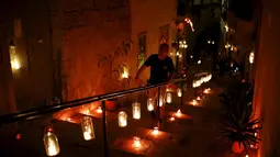Seorang pria menaiki tangga yang telah dihiasi oleh puluhan lilin saat digelarnya festival Birgu di Malta, Sabtu (10/10/2015). Acara ini berlangsung dari 9 - 11 oktober 2015. (REUTERS/Darrin Zammit)