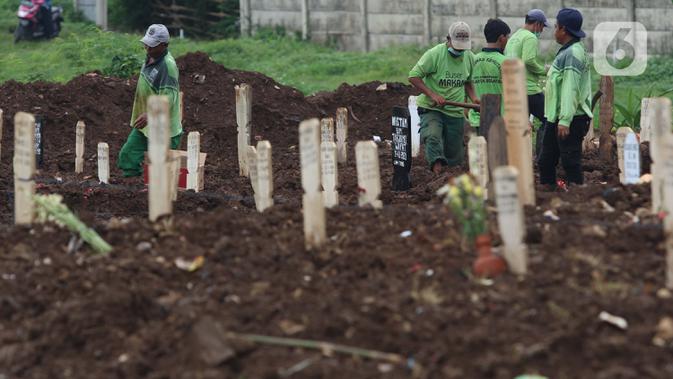 Petugas merapikan area makam jenazah dengan protokol COVID-19 di TPU Srengseng Sawah, Jakarta, Kamis (21/1/2021). Sebagian lahan TPU Srengseng Sawah dijadikan pemakaman jenazah Covid-19 sejak Selasa (12/1) lalu, dengan kapasitas 564 petak makam kini nyaris penuh. (Liputan6.com/Helmi Fithriansyah)
