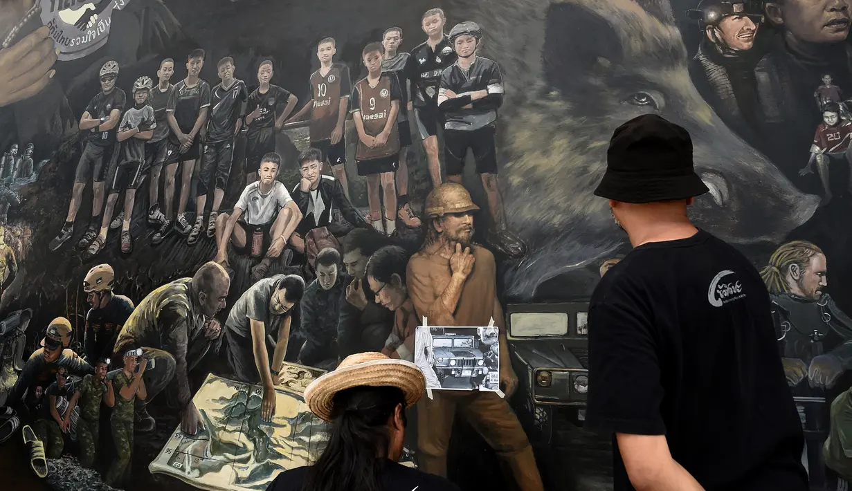 Seniman lokal menyelesaikan mural berjudul 'The Heroes' di Chiang Rai, Thailand, 18 Juli 2018. Lukisan ini menampilkan sejumlah penyelamat dalam upaya penyelamatan 12 remaja dan pelatih sepak bola yang terperangkap di  gua. (AFP/Lillian SUWANRUMPHA)