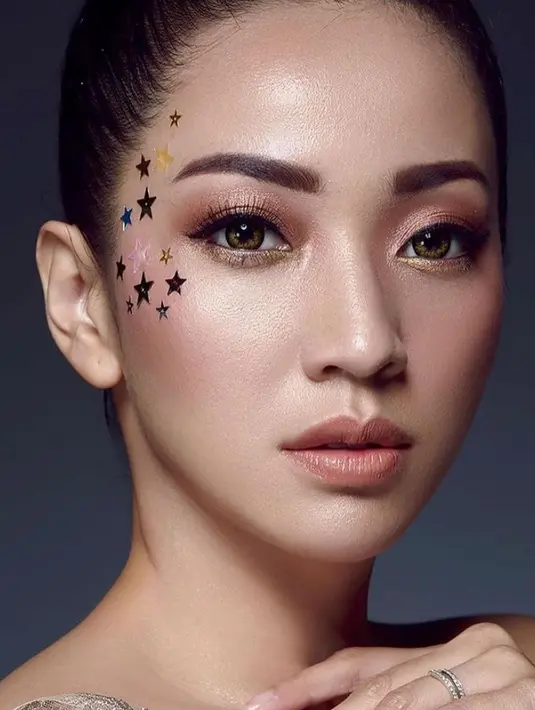 Penampilan wanita berusia 38 tahun ini begitu memesona dengan riasan wajah unik. Diberi tambahan aksesori bintang dibagian tulang pipi, ibu dua anak ini bak ABG. (Liputan6.com/IG/@hestipurwadinata)