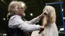 Seorang pria merapihkan bulu anjing Afghan Hound miliknya sebelum tampil pada hari kedua pertunjukan anjing Crufts di National Exhibition Centre di Birmingham, Inggris tengah, (9/3). (AFP Photo/Oli Scarff)