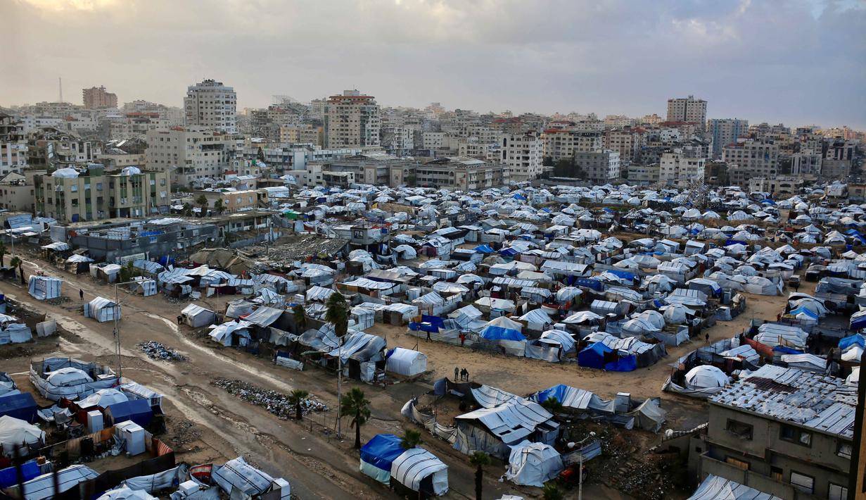 Sementara itu, Kepala Badan Perserikatan Bangsa Bangsa untuk Pengungsi Palestina (UNRWA), Philippe Lazzarini, mengatakan pada Minggu 28 Desember 2025, curah hujan tinggi akan menambah kesengsaraan, keputusasaan, dan angka kematian di Gaza. Tampak dalam foto, tenda-tenda pengungsi Palestina yang melindungi mereka dari kondisi musim dingin yang keras didirikan di lahan terbuka di Kota Gaza, 28 Desember 2025. (Omar AL-QATTAA/AFP)