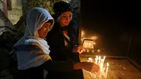 Umat Kristiani Irak menyalakan lilin setelah Misa Malam Natal di Gereja St. Joseph di Baghdad, Irak, Minggu (24/12). (AP Photo / Karim Kadim)