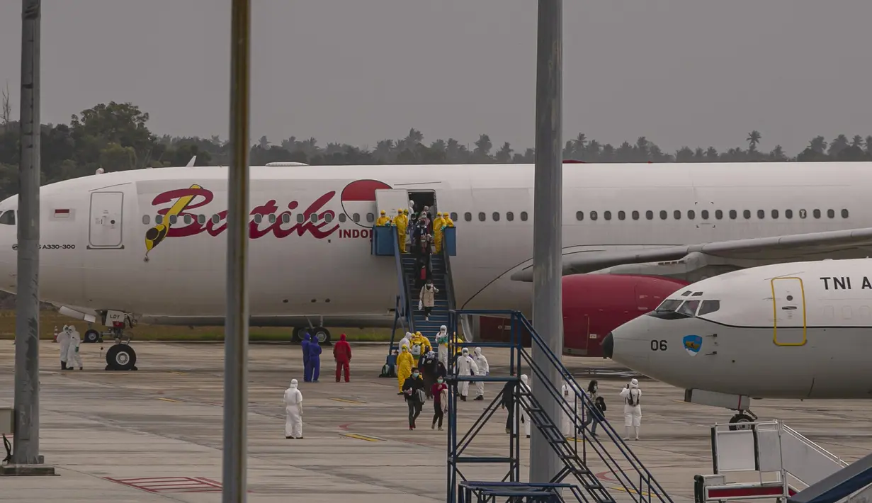 Sejumlah Warga Negara Indonesia (WNI) yang dievakuasi dari Wuhan, China keluar dari pesawat  Batik Air Airbus 330-300CEO di bandara internasional Hang Nadim, Batam, Minggu (2/2/2020). Para WNI langsung ke luar pesawat untuk selanjutnya menuju Natuna, Kepulauan Riau.  (AP Photo/Luth Panjalu)