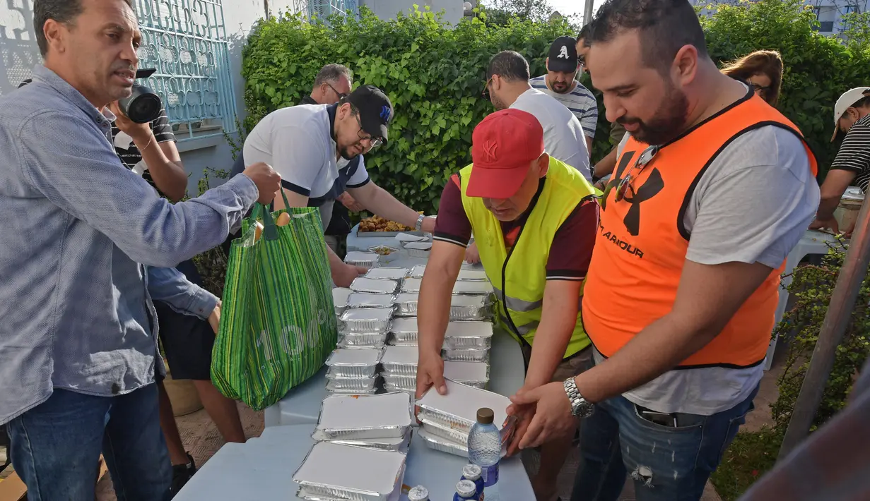 Relawan Tunisia membagikan makanan berbuka puasa gratis selama bulan suci Ramadan di Ariana dekat Tunis (7/5/2020). Masjid-masjid di Aljazair, Maroko dan Tunisia telah ditutup untuk membatasi penyebaran Covid-19, mencegah doa malam khusus. (AFP/Fethi Belad)