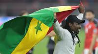Pelatih Senegal, Aliou Cisse melakukan selebrasi sambil membentangkan bendera Senegal usai memastikan menang adu penalti 4-2 (0-0) atas Mesir dalam laga final Piala Afrika 2021 di Stade d'Olembe, Yaounde, Kamerun (6/2/2022). (AFP/Kenzo Tribouillard)