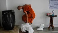 Seorang biksu melepas alat pelindung diri setelah melakukan kremasi untuk korban virus corona COVID-19 di Wat Chin Wararam Worawihan, Bangkok, Thailand, 30 Juli 2021. Kasus COVID-19 di Thailand kini tengah melonjak. (Lillian SUWANRUMPHA/AFP)