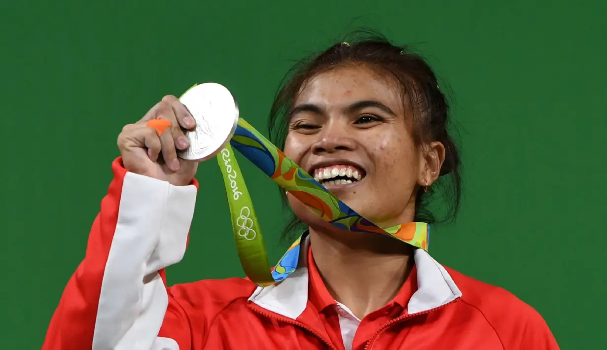 Indonesia meraih medali pertama pada Olimpiade Rio de Janeiro 2016 dari cabang angkat besi, Sabtu (6/8/2016) waktu Brasil atau Minggu (7/8/2016) WIB. Lifter Sri Wahyuni Agustiani (kiri) merebut perak kelas 48 kg putri. (AFP/Goh Chai Hin)