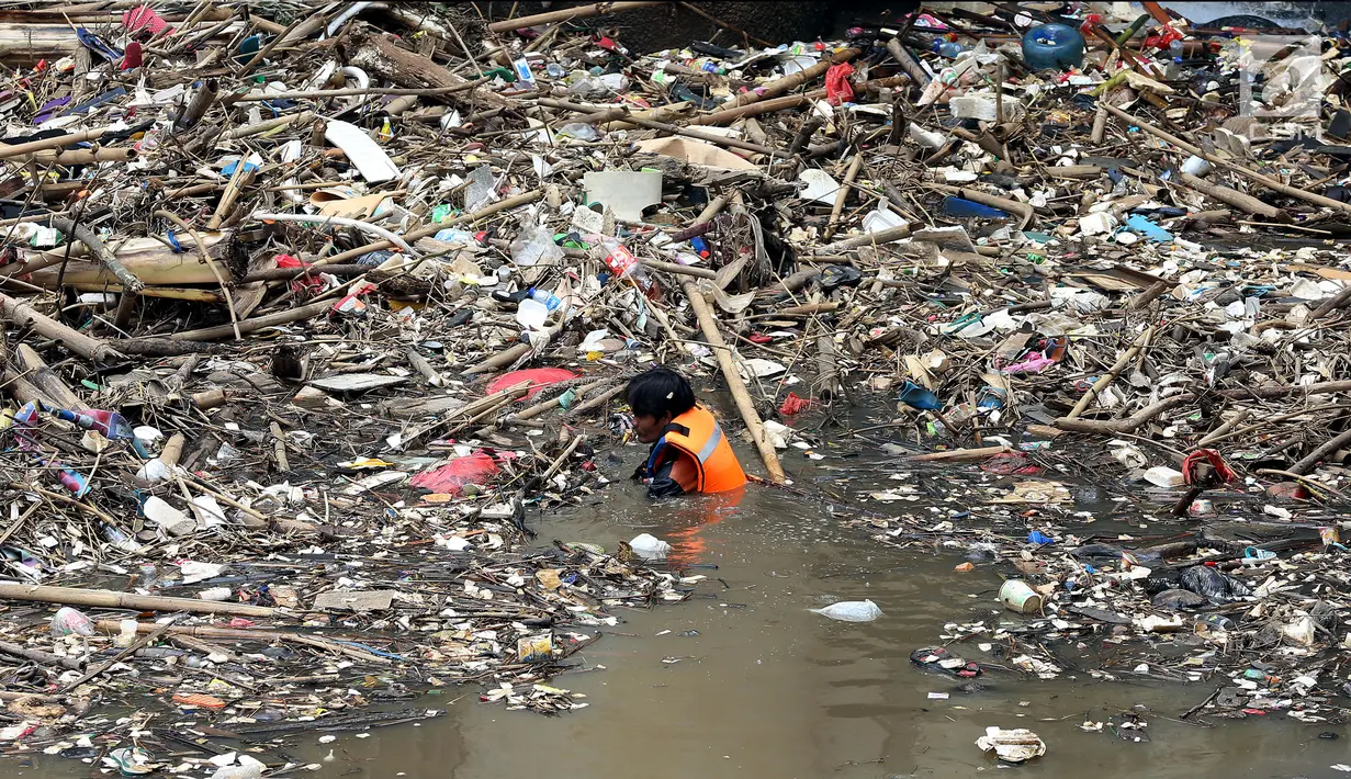 Petugas kebersihan Pemprov DKI membersihkan sampah yang terbawa arus di Pintu air Manggarai, Jakarta, Senin (2/10). Kegiatan ini guna mengurangi penumpukan sampah dan  mencegah datangnya banjir saat hujan deras di wilayah itu. (Liputan6.com/Johan Tallo)