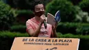 Percibald Garcia menggunakan mikrofon untuk membacakan cerita anak-anak di tengah-tengah kompleks perumahan Tlatelolco di Mexico City pada 18 Juli 2020. Lockdown akibat pandemi corona mmebuat arsitek muda berusia 27 tahun itu memutuskan untuk berbagi cerita menghibur anak-anak. (AP/Marco Ugarte)