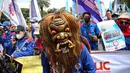 Seorang buruh memakai topeng saat menggelar aksi di kawasan Patung Arjuna Wijaya, Jakarta, Kamis (25/11/2021). Dalam aksinya, ratusan buruh tersebut menuntut pembatalan Omnibus Law Undang-Undang Cipta Kerja dan kenaikan upah 2022. (Liputan6.com/Faizal Fanani)