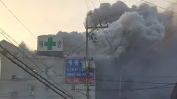 Kepulan asap membumbung tinggi saat petugas pemadam kebakaran berusaha memadamkan api yang membakar rumah sakit Sejong di Milyang, Korea Selatan, Jumat (26/1). Sekitar 200 orang berada di gedung Rumah Sakit saat kebakaran tersebut. (YONHAP / AFP)
