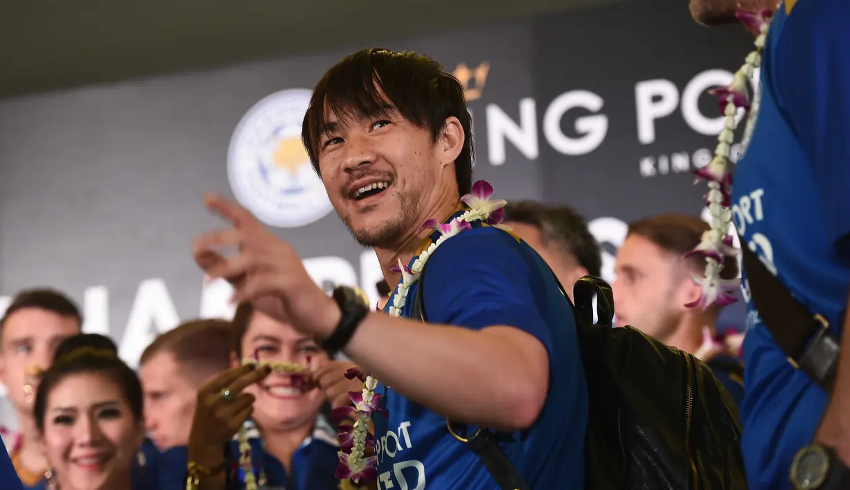Shinji Okazaki melambaikan tangan kepada fans saat disambut dengan kalungan bunga di Bandara International Suvarnabhumi, Bangkok, Thailand, (18/5/2016). (AFP/Lillian Suwanrumpha)